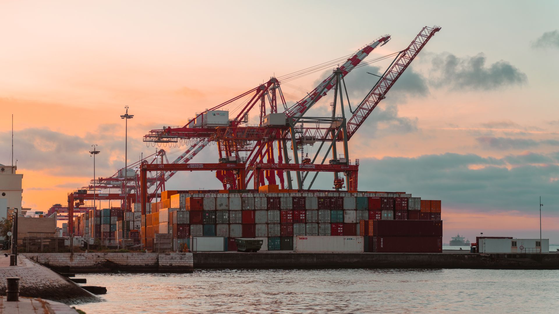 Port maritime au coucher du soleil, conteneurs et grues